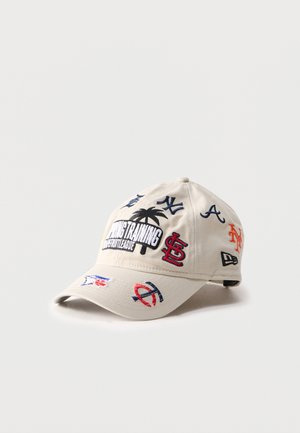 Casquette de baseball beige avec plusieurs logos brodés d'équipes MLB et un palmier accompagné du texte "SPRING TRAINING INTERLEAGUE" à l'avant.