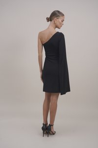 Μαύρο φόρεμα με έναν ώμο και εφαρμοστή σιλουέτα, με ένα μακρύ μανίκι και απαλή υφή, συνδυασμένο με μαύρες γόβες με λουράκι στον αστράγαλο.