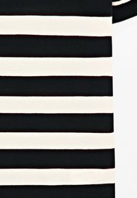 Black and white horizontal stripes on fabric, with a partial sleeve visible in the upper right corner. No people or additional objects present.