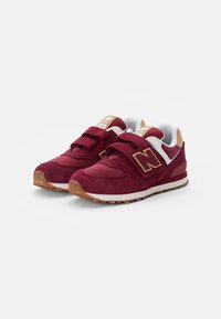 Sneaker in camoscio rosso con linguetta in rete, due cinturini in velcro, tallone bianco e beige, e suola in gomma maculata marrone.