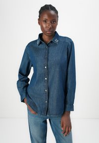 Denim overhemd met knopen in een donkerblauwe tint, versierd met een kraag en knopen op de borst, met lange mouwen en een losse pasvorm.