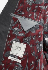 Fodera interna bordeaux con motivo floreale grigio; rifinitura delle tasche grigia; etichetta in tessuto con "next tailoring," taglia "40R," e "skinny fit."