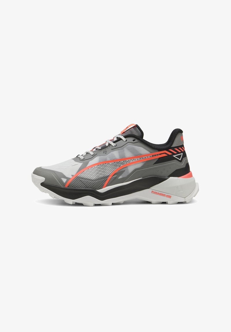 Chaussure de sport grise avec une tige en maille, accents orange et noir, dotée d'une semelle texturée, de détails réfléchissants et de lacets contrastés.