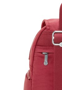 Mochila de tela roja con una superficie texturizada, que presenta un zipper plateado, un bolsillo lateral y una correa de hombro acolchada.