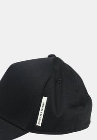 Cappellino da baseball nero realizzato in tessuto liscio, con visiera curvata, etichetta con logo sul lato e dettagli di cucitura.