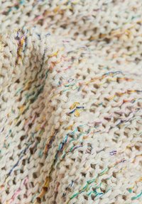 Gestrickter Stoff in Creme mit bunten Sprenkeln. Besitzt ein lockeres, strukturiertes Gewebe, das feine Fasern präsentiert und ein weiches, gemütliches Erscheinungsbild zeigt.