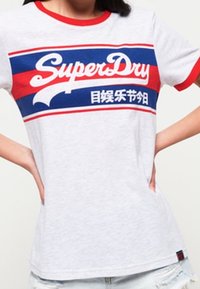 Graues kurzärmliges T-Shirt mit roten Akzenten am Kragen und an den Ärmeln. Mit einem blauen und roten grafischen Logo "SuperDry" über der Brust.