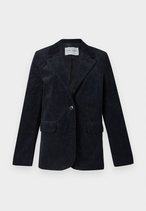 Fløjlsblazer i mørk marineblå. Har hakkede revers, to forlommer, enkelt knaplukning og en glat inderfor.