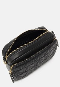 Borsa nera in pelle trapuntata con due scomparti con zip, hardware color oro, finitura liscia e apertura superiore inclinata. Modello testurizzato visibile.