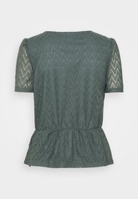 Kortärmad mörkgrön blus i spets med zigzagmönster, rund halsringning och rynkad midja med peplumdetalj, visad liggande framifrån.