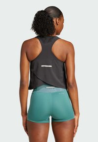 Sort athletic tank top med en løs rygdesign, parret med teal shorts. Refleksstribe på bagdelen af toppen; letvægts, åndbart stof.