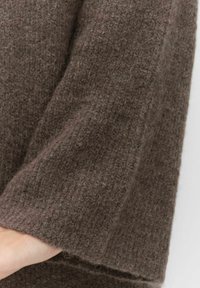 Brun ylletyg med en texturerad yta, som visar en ärmslut. Tyget verkar mjukt och något lurvigt, med en solid färg.