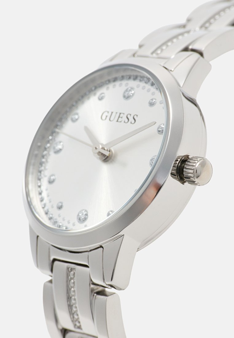 Reloj de pulsera Silver Guess con marcadores de hora de cristal, correa metálica con cristales incrustados y esfera redonda con tres manecillas.