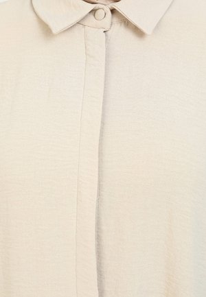 Beige blouse with a textured, lightweight fabric, featuring a classic collar and button closure down the front.