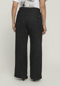 Czarne spodnie o szerokich nogawkach z teksturowanej tkaniny, z wysokim stanem i subtelnym wzorem w drobne plamki, z dwoma tylnymi kieszeniami i luźnym krojem.