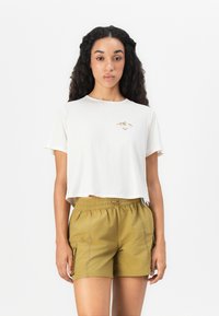 T-shirt blanche raccourcie avec un petit motif de montagne, associée à un short vert olive avec une taille élastique et des poches latérales.