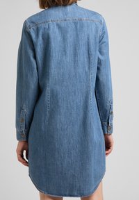 Jeansklänning i ljusblått, långärmade med knappmanschetter, böjd fåll, sömdetalj i bakstycket och en avslappnad passform.