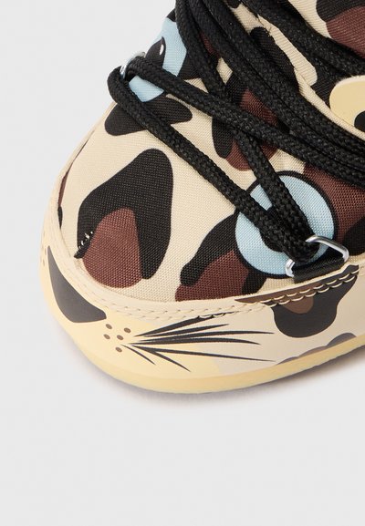 Beige schoen met zwarte veters, stof met luipaardprint, blauw oogachtige ontwerpen en zwarte snorhaar details op het teen gebied.