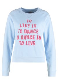 Světle modrý svetr s dlouhým rukávem s růžovým nápisem "ŽÍT ZNAMENÁ TANČIT, TANČIT ZNAMENÁ ŽÍT" na přední straně.