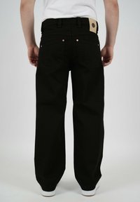 Svarta, vida jeans i kraftigt tyg med bakfickor, guldfärgade detaljer och en patch nära midjan.