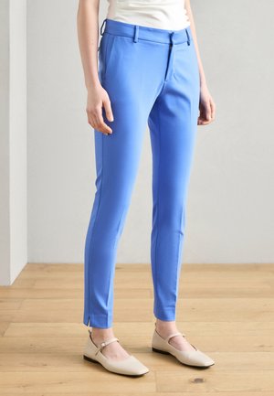Blue tailored trousers made of smooth fabric, featuring a straight cut, front pockets, and split hems. Paired with beige flat shoes.