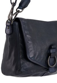 Námořnická kůže taška přes rameno s texturovaným povrchem, klopovým uzávěrem a kovovým kroužkem v blízkosti uchycení popruhu. Nastavitelný ramenní popruh.