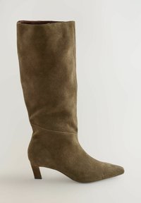 Bota de tacón alto en ante verde oliva con punta afilada y caña ajustada, que presenta una textura suave y un diseño estructurado.
