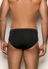 Costumi da bagno neri con una cintura liscia ed elastica. Presentano un design aderente che si adatta al corpo, mettendo in risalto un'estetica minimalista.