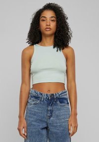 Svetlo modrý rebrovaný crop top s vysokým golierom, skombinovaný s vysokými, zladenými modrými riflami s gombíkovým zapínaním a vreckami.