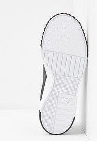Semelle de chaussure avec une surface en caoutchouc blanche texturée et un motif de traction noir. Comprend un logo et des rainures horizontales pour l'adhérence.