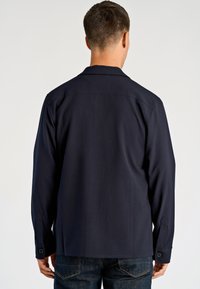 Marineblauw shirt met lange mouwen, voorzien van een kraag, knoopmanchetten en een gladde stofafwerking. Achteraanzicht toont een minimalistisch ontwerp zonder versieringen.