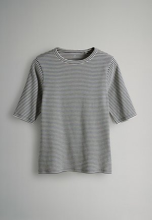 Must-valge triibuline T-särk, mis on valmistatud pehmest kangast. Omadused: ümar kaelus ja lühikesed varrukad, lõdvestunud istuvus.