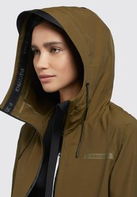 Olivgrön hoodie-jacka med svarta detaljer, med en logotyp, dragkedjestängning och justerbara snoddar vid huva och nederkant.