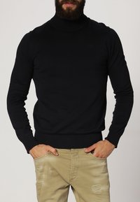 Czarny sweter z golfem o dopasowanym kroju, z długimi rękawami oraz prążkowanymi mankietami i dołem, wykonany z miękkiej, teksturowanej tkaniny.