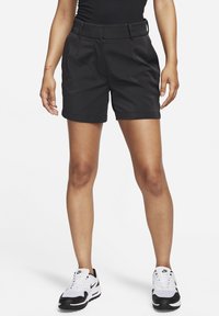 Shorts negros de tela suave, con cintura ajustada, bolsillos frontales y dobladillo enrollado. Combinados con zapatillas blancas y negras.