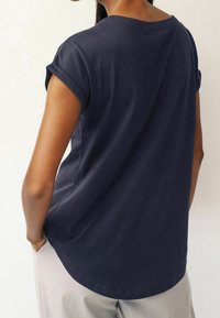 Navyblauwe katoenen T-shirt met opgerolde mouwen en een ronde halslijn, voorzien van een gebogen zoom en een gladde textuur.