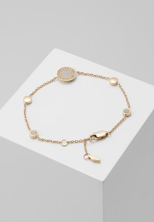 Bracelet chaîne en or avec incrustations rondes argentées scintillantes et fermoir homard, présenté sur un cube blanc sur fond gris.