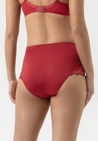 Rode hooggeplaatste slip met gladde stof, kantdetail en een naadloos ontwerp aan de achterkant voor comfort en bedekking.