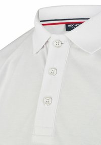 Witte polo met een gestructureerde stof, voorzien van een klassieke kraag, een drieknops sluiting en een rode en blauwe gestreepte accent binnenin de kraag.