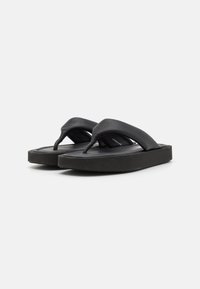 Sorte flip-flops med en bred, glat rem og en tekstureret sål. Kraftig sort sål, der giver støtte og stabilitet. Minimalistisk design.
