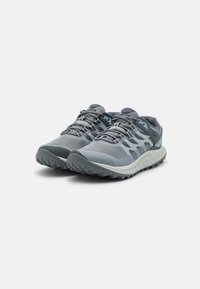 Scarpe da trail running grigie con tomaia in rete, sovrapposizioni rinforzate, chiusura con lacci e suola robusta per una migliore aderenza. Caratterizzate da accenti blu chiaro.