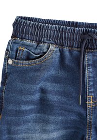 Jeansshorts med elastiskt midjeband och dragsko, mörkblå färg med blekta partier, kontrasterande gul söm och sidoficka.