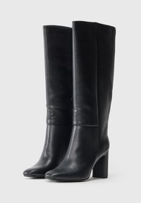 Μαύρες δερμάτινες μπότες ως το γόνατο με λείο φινίρισμα, μυτερή μύτη και τετράγωνη φτέρνα. Απλός σχεδιασμός με ελάχιστες λεπτομέρειες.