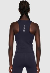 Navyblauwe sporttanktop met een racerback ontwerp. Met "ATW" in het wit gedrukt op de achterkant. Strakke pasvorm, gladde textuur en elastische stof.