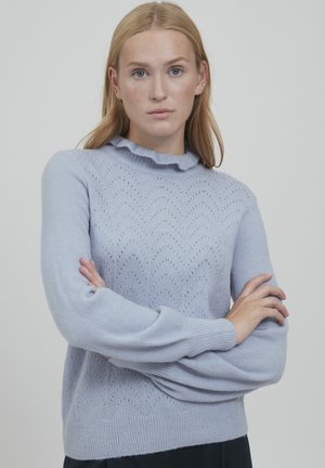 Hellblauer gestrickter Pullover mit einem gewellten Halsauschnitt, gerippten Bündchen und einem komplexen Muster aus Löchern im Chevron-Design.