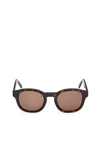 Verres rectangulaires teintés marron avec des lunettes à grosse monture en écailles de tortue, nom de la marque subtilement imprimé dans le coin supérieur du verre droit.