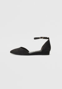 Bailarinas de ante negro con punta afilada, correa al tobillo y tacón bajo. Presentan una textura suave y un diseño minimalista.