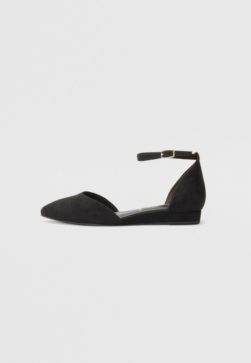 Bailarinas de ante negro con punta afilada, correa al tobillo y tacón bajo. Presentan una textura suave y un diseño minimalista.