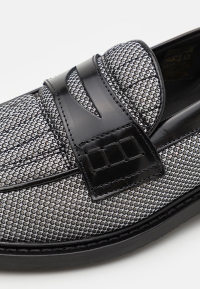 Schwarze Slipper mit einer strukturierten silbernen Netz-Oberfläche, glatten schwarzen Lederakzenten und einem dekorativen Riemen über dem Spann. Gummisohle.