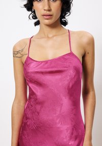 Satijnen rozenkleurige slipdress met dunne bandjes, voorzien van een bloemenpatroon en een gladde textuur. Sluit nauw aan op het lichaam en accentueert de lichaamsvorm.